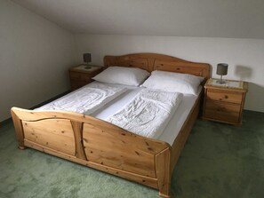 A wooden bed with a headboard, two nightstands, and a green carpet.