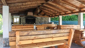 An outdoor wooden pavilion with benches and a stone fireplace.