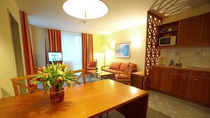 A dining area with a wooden table, chairs, a vase of flowers, a sofa, and a television in the background. - Beach Park Heringsdorf - near the beach / first row - apartment 3. 24 (Heringsdorf)