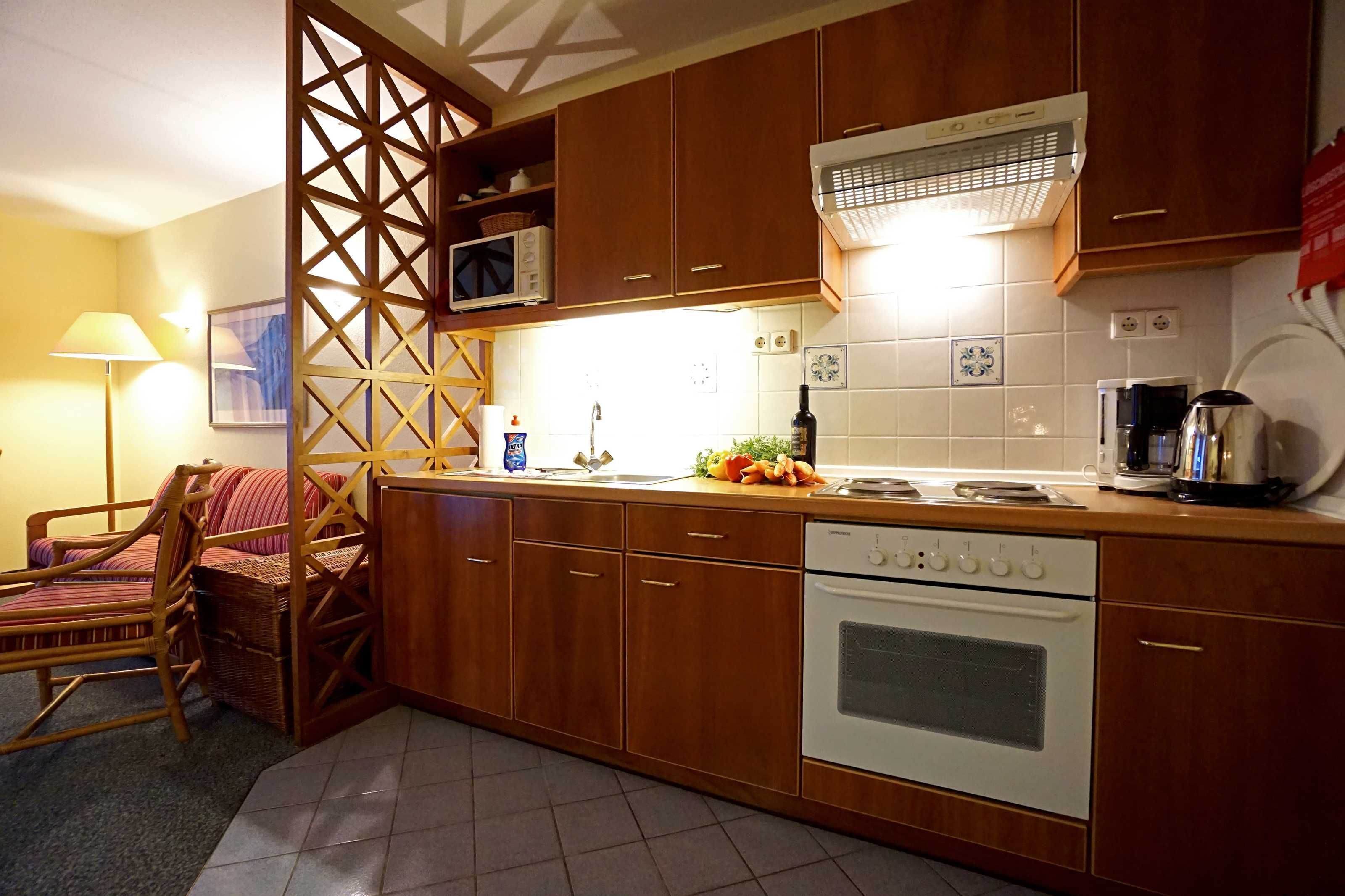 A kitchen with wooden cabinets, a microwave, an oven, and a coffee maker.
