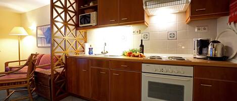A kitchen with wooden cabinets, a microwave, an oven, and a coffee maker.
