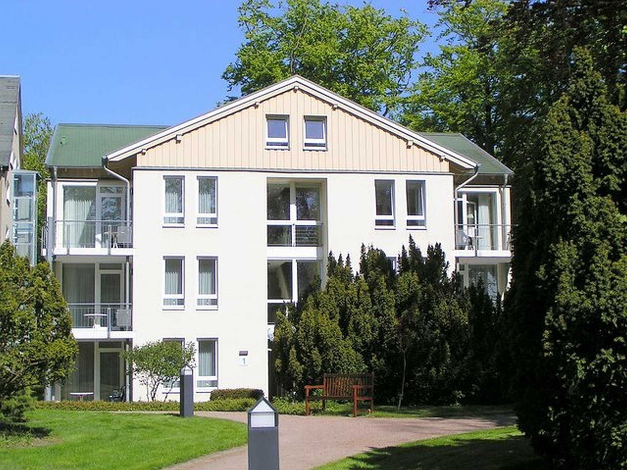 Ein mehrgeschossiges Wohngebäude mit symmetrischer Fassade, großen Fenstern und einem zentralen Eingang.