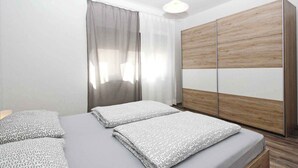 Un dormitorio con dos camas, un armario de madera y una ventana con cortinas.