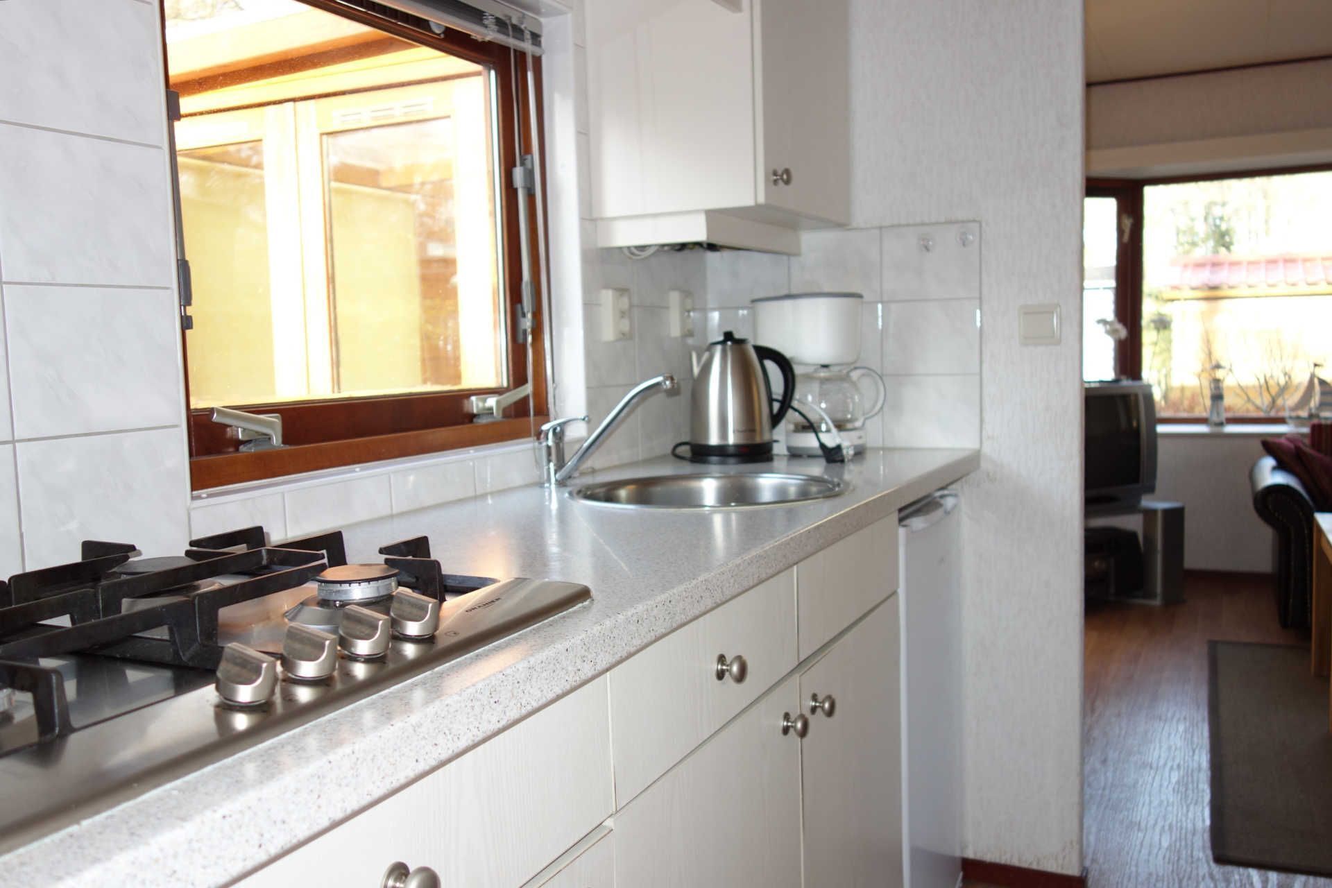 A modern kitchen with a gas stove, stainless steel sink, and white cabinets.
