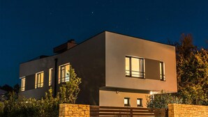 A modern two-story house with large windows and a stone wall in front. - Beach front home in Premantura (Premantura)