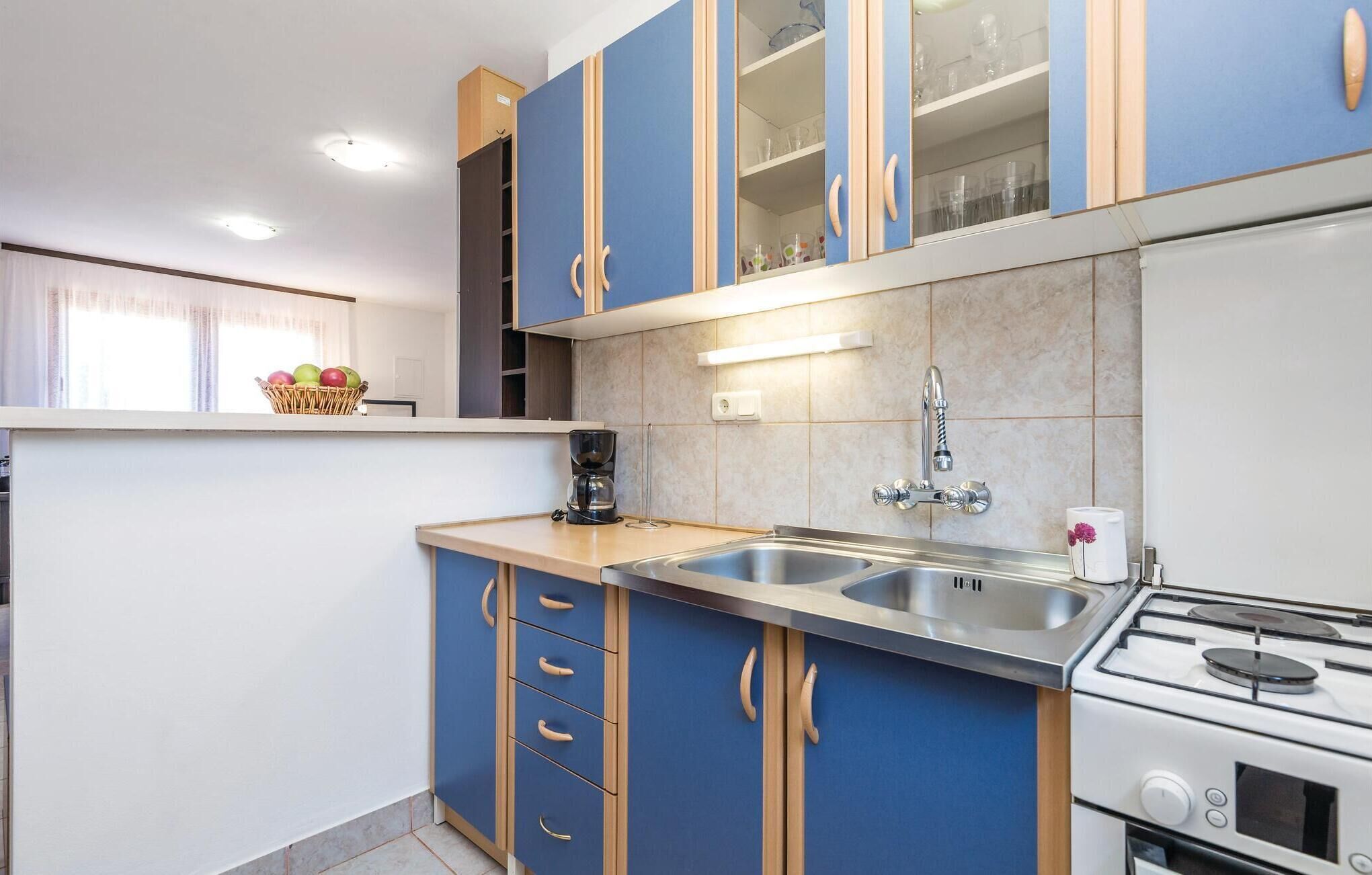 Cuina moderna amb armaris blaus, un rentaplatets d'acer inoxidable i una cuina a gas.