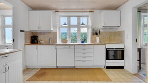 Una cocina moderna con armarios blancos, horno empotrado y un amplio ventanal que proporciona luz natural.