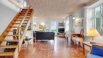 Un vaste espace de vie comprenant un escalier en bois, une table à manger et un téléviseur.