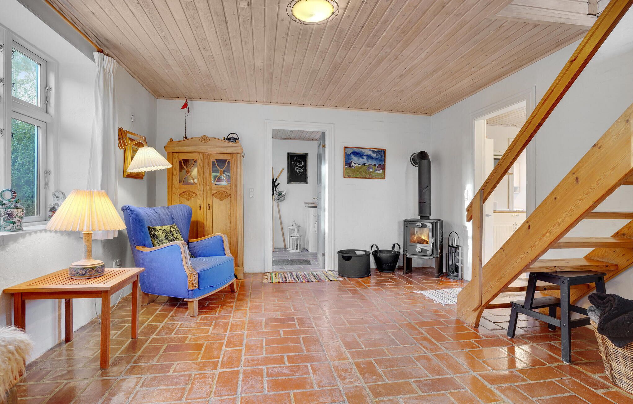 Uma sala de estar aconchegante com uma poltrona azul, um armário de madeira, uma lareira e uma escada.