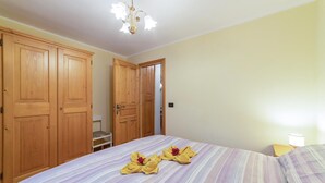 Una camera da letto con un letto, un armadio in legno e una porta che dà su un'altra stanza.