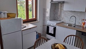 A compact kitchen with a built-in oven, a sink, and a window with a view of greenery.