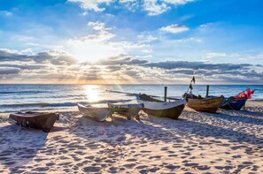 A beach with several boats anchored on the sand and the ocean in the background.