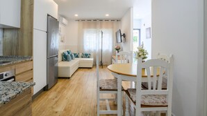 A modern kitchen with a built-in oven, a refrigerator, and a wooden countertop. There is a dining area with a wooden table and white chairs. - Cozy home in Málaga with WiFi (Málaga)