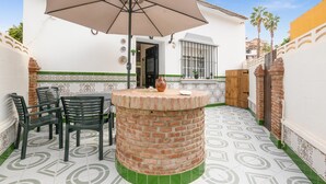 A patio with a brick table, chairs, and an umbrella. - Cozy home in Málaga with WiFi (Málaga)