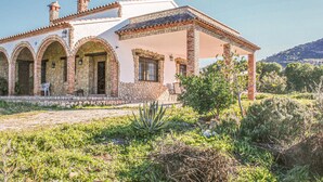 Eine Villa im mediterranen Stil mit Stein-Fassade, Rundbogenfenstern und einem Ziegeldach.