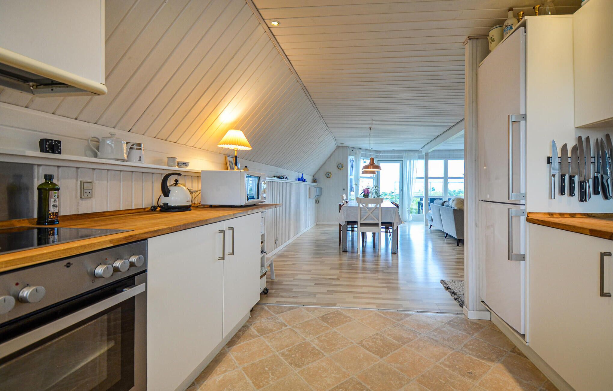 A kitchen with a wooden countertop, white cabinets, and a tiled floor.