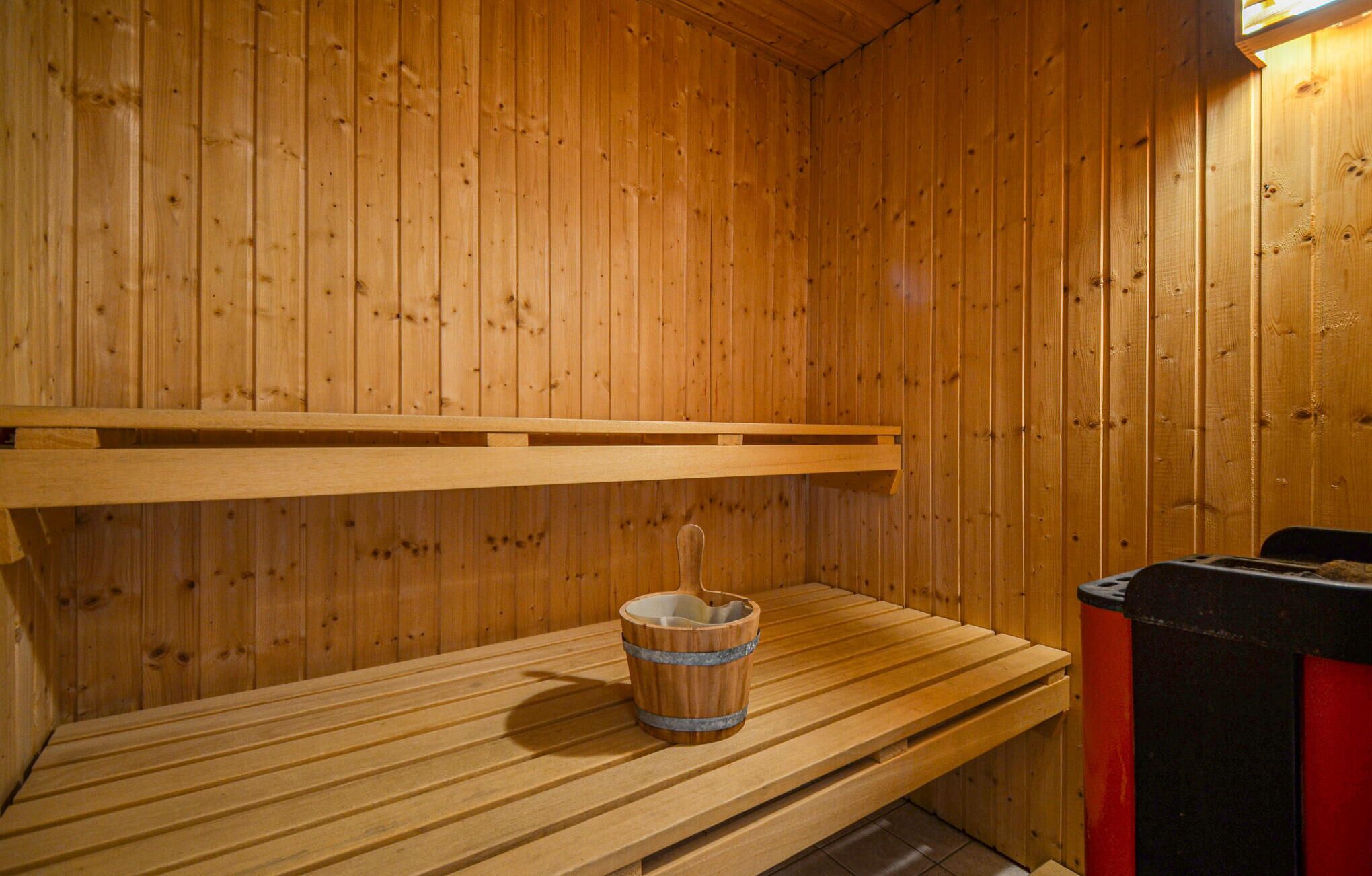 Un sauna en bois avec des bancs et un seau.