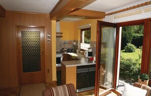 Une cuisine compacte équipée d’un four encastré, d’une machine à café et d’une fenêtre donnant sur un jardin.