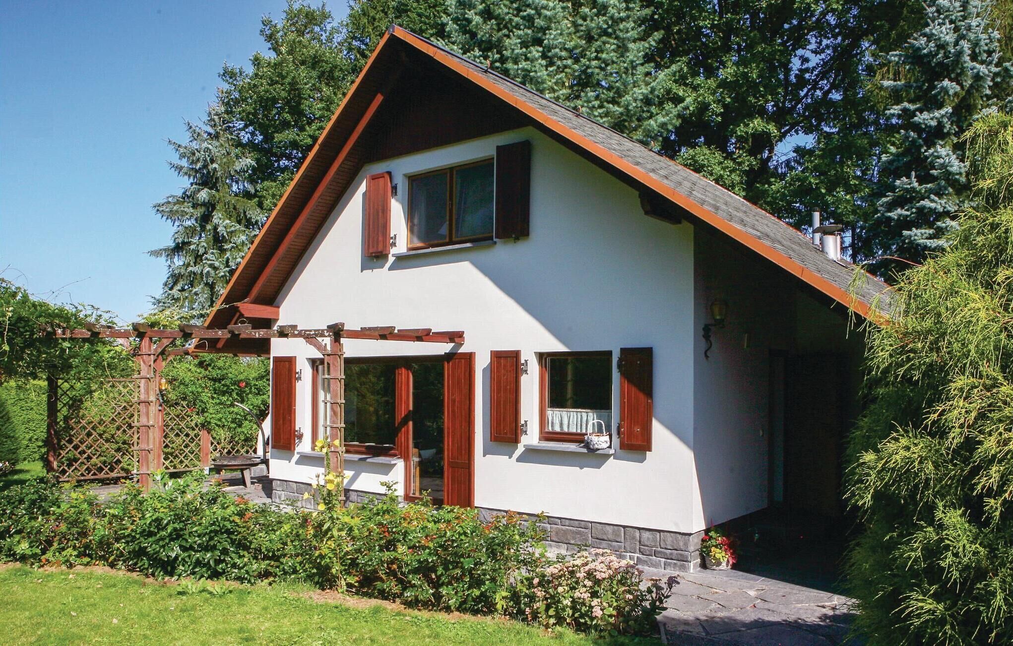 Une maison à deux étages, avec un toit en pente, des volets en bois et des fondations en pierre.