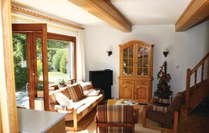 Un salon confortable avec un canapé, des fauteuils, un meuble en bois et un téléviseur.