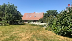 A house with a red tiled roof, surrounded by a well-maintained lawn and various shrubs. - Vacation home 1 - Holiday homes Michaelis 1 to 4 in Quilitz (Rankwitz)