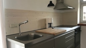 A modern kitchen with stainless steel appliances, a wooden cutting board, and a coffee maker. - Vacation home 1 - Holiday homes Michaelis 1 to 4 in Quilitz (Rankwitz)