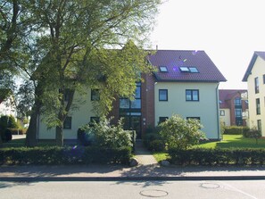 Ein Wohngebäude mit Ziegeldach, mehreren Fenstern und einem gepflegten Garten.