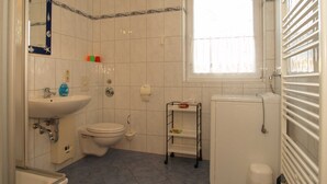 Et badeværelse med toilet, vask og vindue.