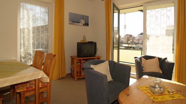 En stue med spisebord, to stole, sofa og fjernsyn.