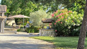A patio with a table and chairs, a stone structure with a bench, and a garden with pink flowers. - Gorgeous home in St.Aubin de Cadelech (St.Aubin de Cadeleche)