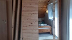 A room with a slanted ceiling, a bed with a checkered bedspread, and a window with curtains. - Holiday home with garden and barbecue (Balatonsz��rszó)