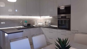 A modern kitchen with white cabinets, a built-in oven, and a coffee maker. - Holiday home with garden and barbecue (Balatonsz��rszó)
