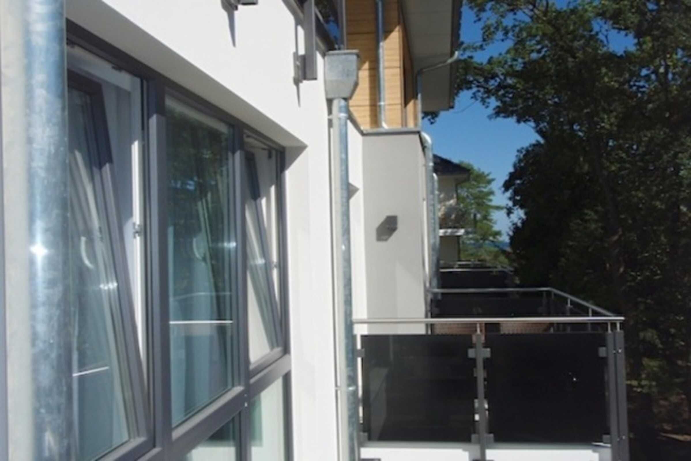 Ein modernes Gebäude mit großen Fenstern, einem Balkon und einem Metallgeländer.
