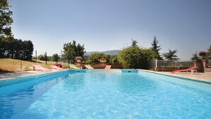 A clear blue pool with lounge chairs and a slide, surrounded by trees and a view of hills. - 3 bedroom cozy home in Sault (Sault)