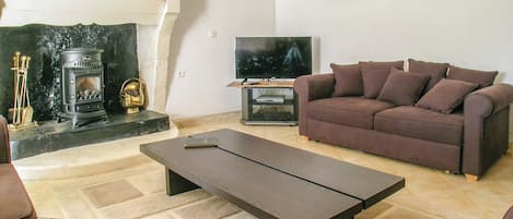 Een woonkamer met een open haard, een bank, een salontafel en een televisie.