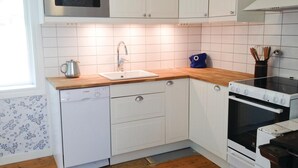 A compact kitchen with white cabinetry, a Bosch dishwasher, a microwave, and a stove. - Cozy home in Gislaved with house sea view (Gislaved)