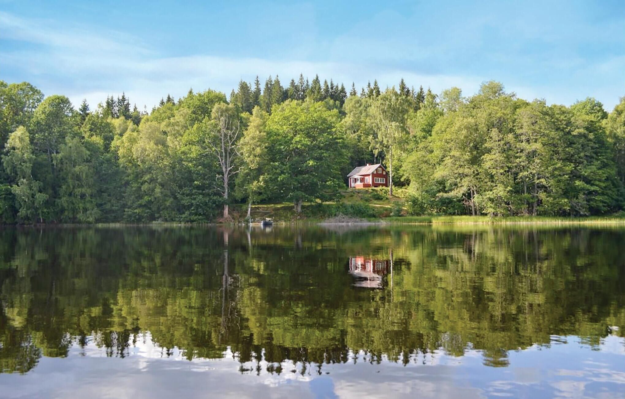 Ein Haus, umgeben von dichtem Wald und einem stillen See.