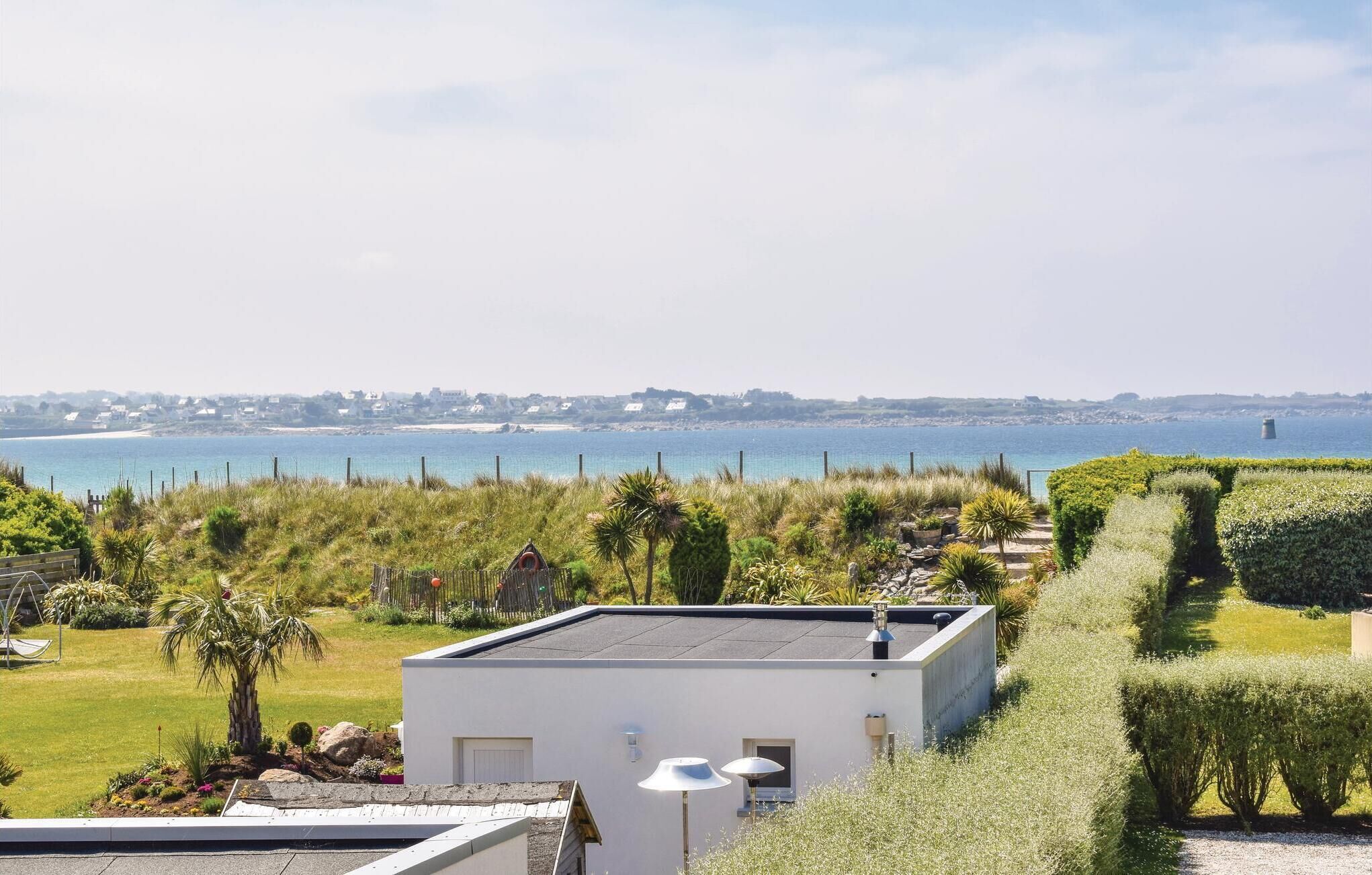 Une propriété située sur la côte, avec un bâtiment blanc, une vue sur la mer et de beaux jardins bien entretenus.