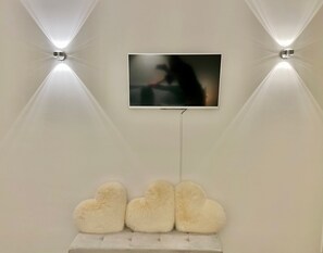A television mounted on a wall with two wall-mounted lights on either side. - Apartment - PALACE AM SEE (Tegernsee)