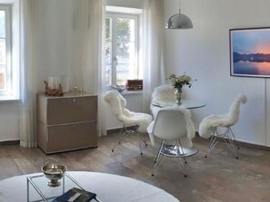 A modern dining area with a round table, white chairs, and a vase of flowers. - Apartment - PALACE AM SEE (Tegernsee)