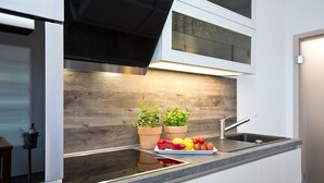 Una cocina moderna con horno integrado, pileta de acero inoxidable y protector de cocina de madera.