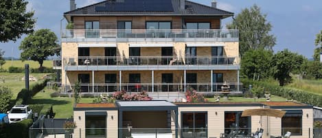 A multi-story building with balconies, a covered outdoor seating area, and a garden.