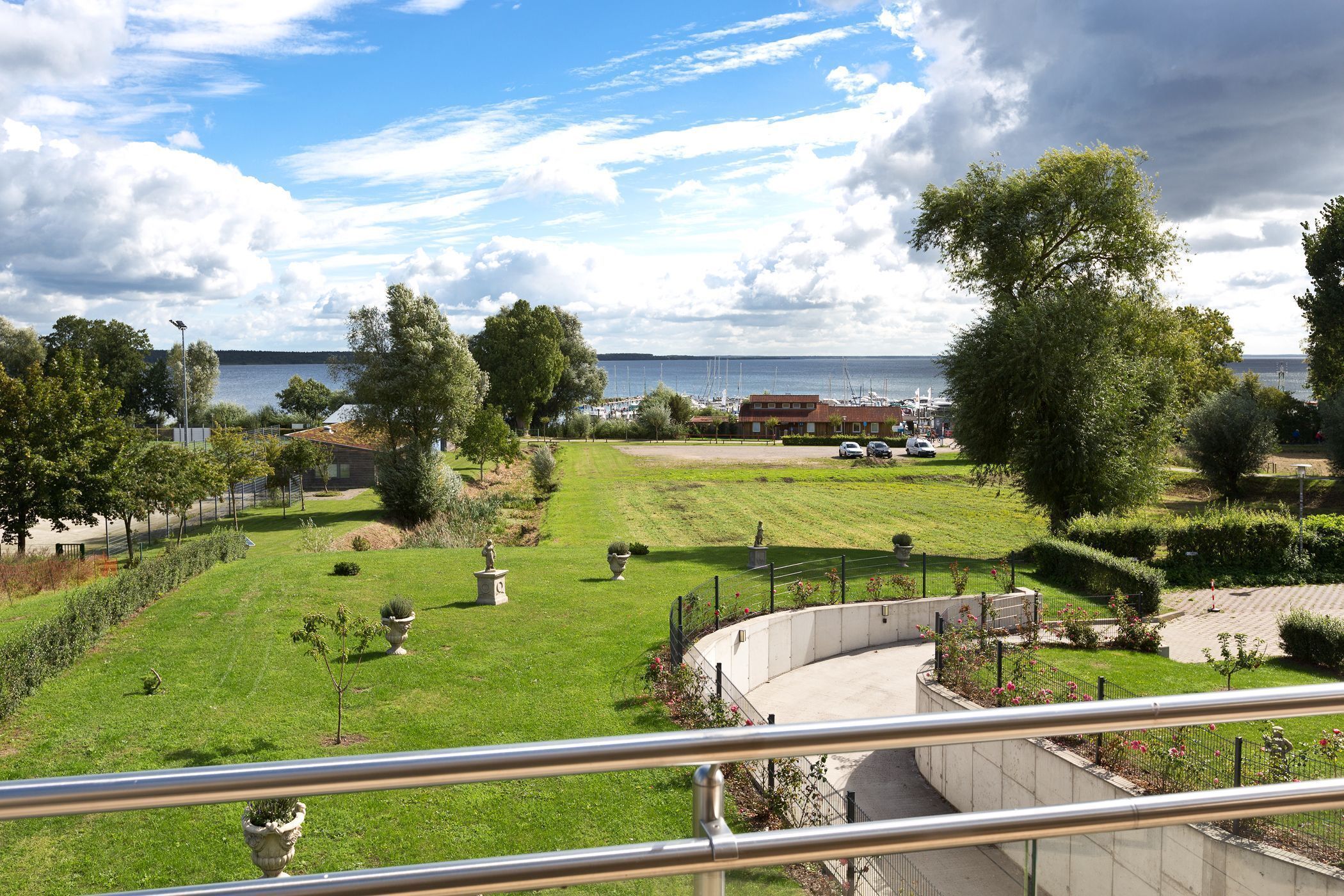 A landscaped garden with a pathway, benches, and a view of the sea.