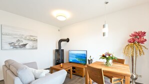 Una sala de estar moderna con un sofá, una mesa de comedor de madera, un televisor y un jarrón decorativo.