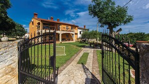 Una casa de dos pisos con un camino de piedra que lleva a una entrada con portón.