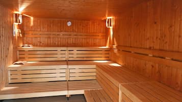 Un sauna en bois, doté de bancs et de lampes fixées au mur.