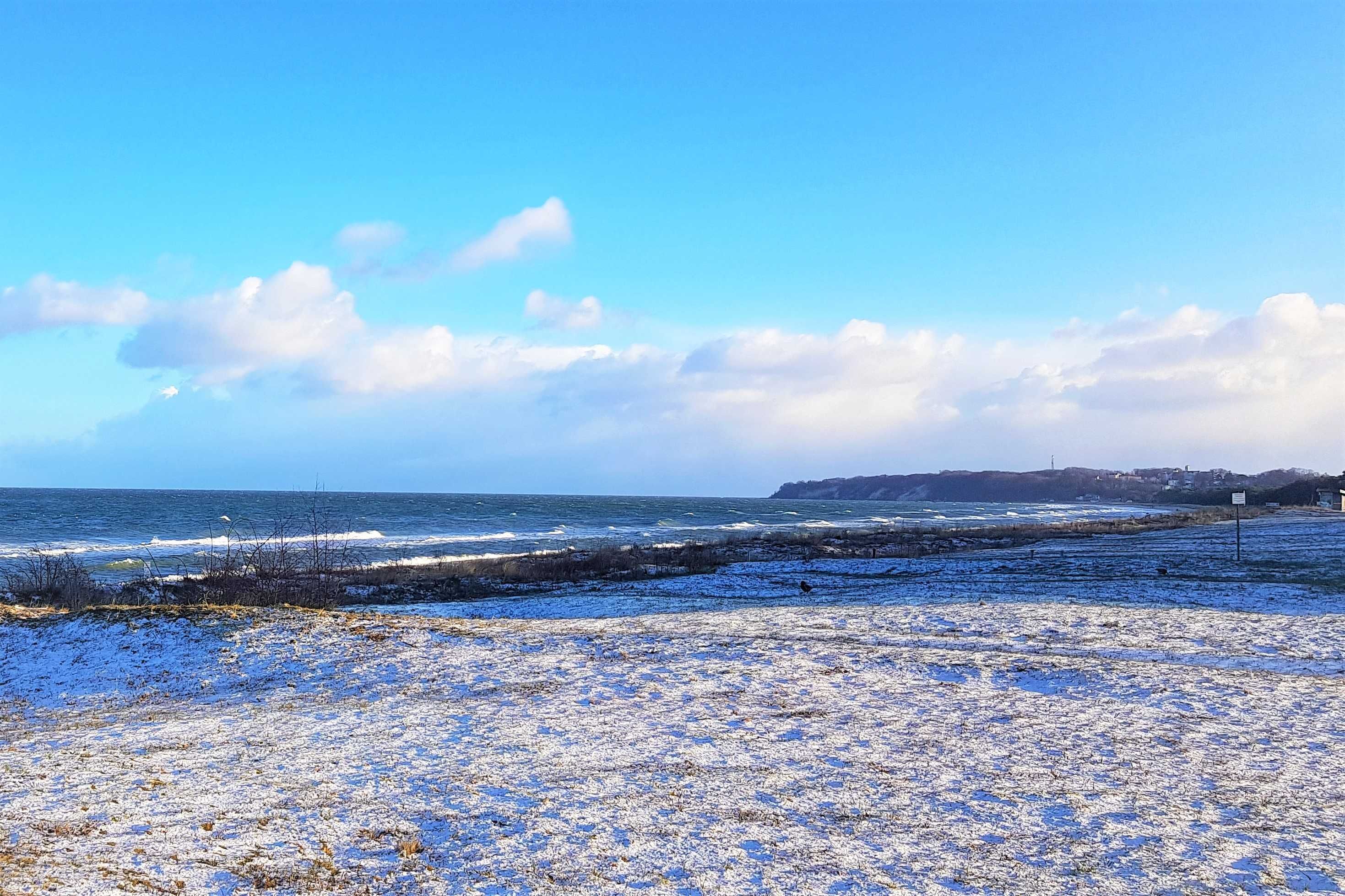 Ett kustlandskap med en klar himmel, en sandstrand och en avlägsen kustlinje.