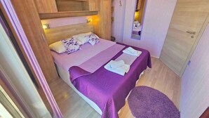 Une chambre à coucher avec un lit, une armoire en bois, un miroir et une petite table ronde.