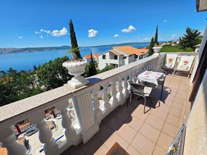 A balcony with a table and chairs, overlooking a body of water and buildings.