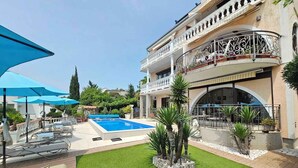 Un espace piscine comprenant des chaises longues, une petite piscine et une pelouse bien entretenue.